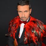 L'homme ange en smoking noir avec une cape en plumes rouges