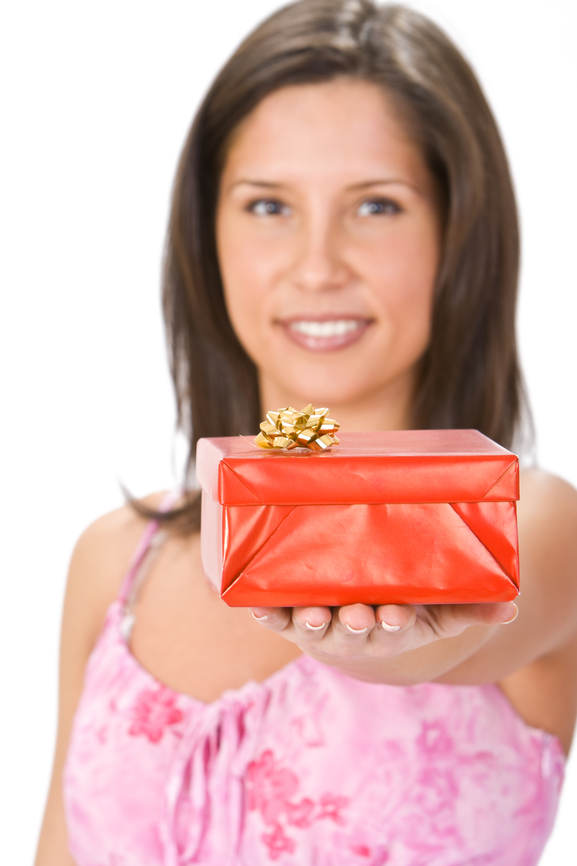 Une femme, la quarantaine au sourire très agréable offrant un cadeau à autrui.