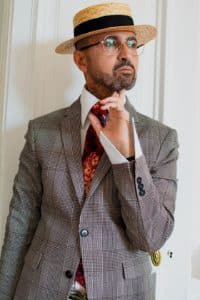 OUTFIT homme plutôt originale avec chapeau cravate et pochette. Des lunettes de vue binocles et un pantalon motif animalier. Très dandy.