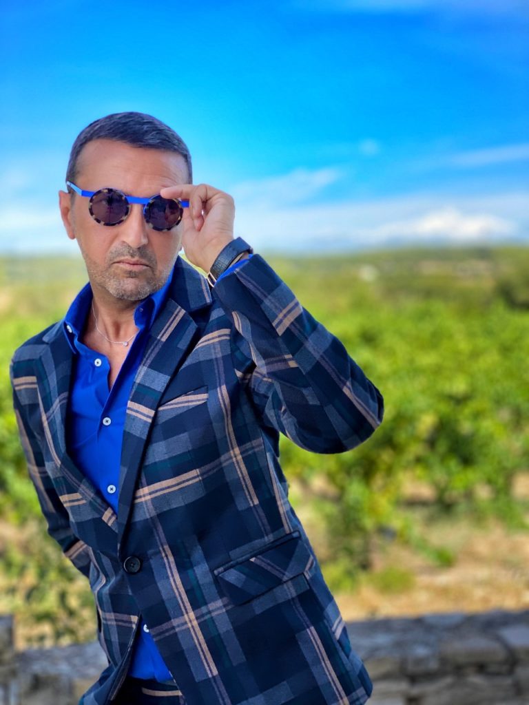 Le model porte un très beau costume à carreaux bleus, d’une coupe contemporaine et slim fit assorti d’une chemise bleu roi et une paire de chaussures mocassins bleues. L’accessoire principal est une paire de lunettes de soleil bleue pour assure un très beau monochrome bleu.